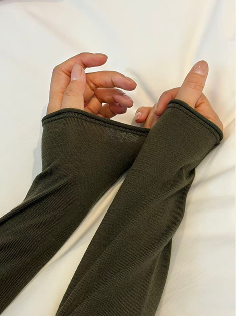 Close-up of olive green seamless knit arm cuffs showing fine gauge texture and rolled edge finish